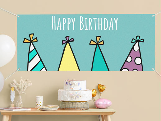 A vinyl banner featuring birthday party hats installed on a wall