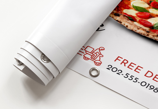 Vinyl banner with grommets rolled halfway showcasing pizza restaurant advertisement